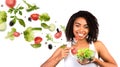 Healthy eating. African American lady with bowl of salad and flying veggies on white background, blank space. Panorama