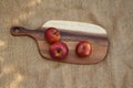 Three red apples on a wooden cutting board