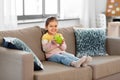 Happy little girl with apple sitting on sofa Royalty Free Stock Photo