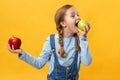 Healthy eating concept. A child bites an apple. Little girl on a yellow background Royalty Free Stock Photo