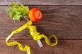 Healthy eating concept. Fork and vegetable with measure tape and fresh tomato on wooden desk. Top view and Copy space Royalty Free Stock Photo