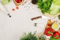 Healthy eating concept - fresh raw green salad, cherry tomatoes, paprika, spinach, cabbage and olive oil on white wood board, top Royalty Free Stock Photo