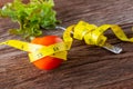 Healthy eating concept. Tomato with measure tape, Fork and vegetable with measure tape on wooden desk Royalty Free Stock Photo