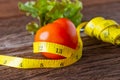 Healthy eating concept. Tomato with measure tape, Fork and vegetable with measure tape on wooden desk Royalty Free Stock Photo