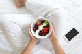 Healthy eating concept. Women`s hands holding bowl with cottage cheese with cream, strawberry, cherry, gooseberry and blueberry Royalty Free Stock Photo