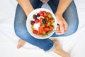 Healthy eating concept. Women`s hands holding bowl with muesli, yogurt, strawberry and cherry. Top view. Lifestyle