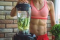 Close up of young woman with blender and green vegetables making detox shake or smoothie at home Royalty Free Stock Photo