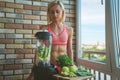 Close up of young woman with blender and green vegetables making detox shake or smoothie at home Royalty Free Stock Photo