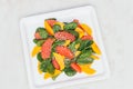 Healthy eating and dieting concept. Fresh salad of mango, grapefruit, spinach and hempseed on white square plate. Top view.