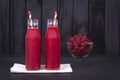 Raspberries juice in a two glass bottle and raw raspberry on black wooden background, close up Royalty Free Stock Photo