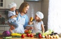 Healthy eating. Happy family mother and children prepares vegetable salad Royalty Free Stock Photo