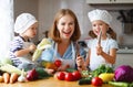 Healthy eating. Happy family mother and children prepares vegetable salad Royalty Free Stock Photo