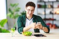 Healthy eating. happy young asian man eating salad with phone and tablet pc in morning Royalty Free Stock Photo