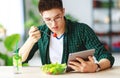 Healthy eating. happy young asian man eating salad with phone and tablet pc in morning Royalty Free Stock Photo