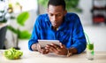 Healthy eating. happy young black man eating salad with phone and tablet pc in morning Royalty Free Stock Photo