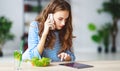 Healthy eating. happy young girl eating salad with tablet pc in morning in kitchen Royalty Free Stock Photo