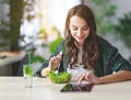 Healthy eating. happy young girl eating salad with tablet pc in the morning in kitchen Royalty Free Stock Photo
