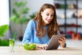 Healthy eating. happy young girl eating salad with tablet pc in morning in kitchen Royalty Free Stock Photo