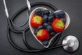 Healthy eating and heart health concept with a heart shaped bowl with blueberries and a stethoscope each blueberry is packed full