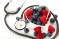 Healthy eating and heart health concept with a heart shaped bowl with mixed berries and a stethoscope each berry is packed full of Royalty Free Stock Photo