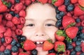 Healthy eating. Kids face with berries mix of strawberry, blueberry, raspberry, blackberry. Royalty Free Stock Photo