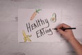 Healthy eating sign with doodles of diet snack foods real hand holding pencil