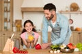 Healthy eating. Smiling child girl helping dad cooking vegetable salad, holding and showing fresh yellow bell pepper Royalty Free Stock Photo