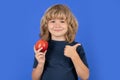 Healthy eating. Smiling child with thumbs up hold apple. Portrait of of cute boy kid isolated over studio background. Royalty Free Stock Photo