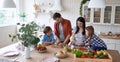 Healthy eating. Young beautiful family cooking together in the modern kitchen at home. Mother and father teaching two