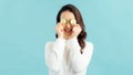 Healthy eyes. Beautiful young woman holding slices of cucumber in front of her eyes while standing against blue background Royalty Free Stock Photo