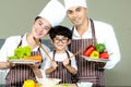 Healthy Family. Father and Mother with son cooking salad fresh vegetables for diet in kitchen.  Smiling kid boy help family making Royalty Free Stock Photo