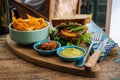 Healthy Fast food. burger with a chop, lettuce with sweet potatoes fries and two sauces. Tasty sandwich for lunch on wooden table