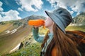 Healthy female hiker drinks water on a hike in nature. Beautiful young woman happy on a hike with a bottle of water Royalty Free Stock Photo