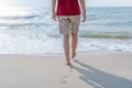 Healthy female legs with droplets walking to leave footprints barefoot alone on sandy sea beach in summer