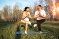 Healthy and fit mixed race couple practice yoga stretching outdoors together in the expansive lawn lush green park Royalty Free Stock Photo