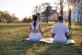 Healthy and fit mixed race couple practice yoga stretching outdoors together in the expansive lawn lush green park Royalty Free Stock Photo