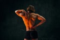 Healthy fit relief ack. Rear view of young shirtless man with muscular body standing in underwear against dark textured Royalty Free Stock Photo