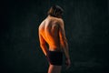 Healthy fit relief ack. Rear view of young shirtless man with muscular body standing in underwear against dark textured Royalty Free Stock Photo