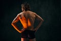 Healthy fit relief ack. Rear view of young shirtless man with muscular body standing in underwear against dark textured Royalty Free Stock Photo