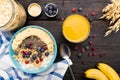 Healthy fitness breakfast with fresh orange juice: oatmeal with bananas, blueberries and cranberries, chia seeds and yogurt on