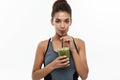 Healthy and Fitness concept - Beautiful American African lady in fitness clothing drinking healthy vegetable drink
