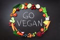 Healthy food background. Circle of fresh vegetables, fruits, nuts, berries with handwritten phrase Go Vegan on black