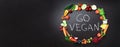 Healthy food background. Circle of fresh vegetables, fruits, nuts, berries with handwritten phrase Go Vegan on black