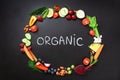 Healthy food background. Circle of fresh vegetables, fruits, nuts, berries with handwritten phrase Organic on black Royalty Free Stock Photo