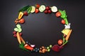 Healthy food background. Circle of organic vegetables, fruits, nuts, berries with copy space on black chalkboard. Top
