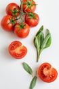 Healthy food background - raw tomatoes and wild herbs on white background, vibrant colours