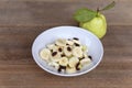 Healthy food banana slide guava block and raisins in white bowl on wood table. With copy space for text or design