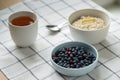 Healthy food breakfast with oatmeal porridge in bowl with summer berries, slice of butter, mug tea.