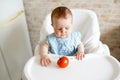 Healthy food for children. Adorable little baby sitting in her chair and playing with vegetables . small girl eat tomato