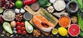 Healthy food clean eating selection: fish, fruit, nuts, vegetable, seeds, superfood, cereals, leaf vegetable on black concrete